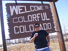 colorado man standing next state welcome sign